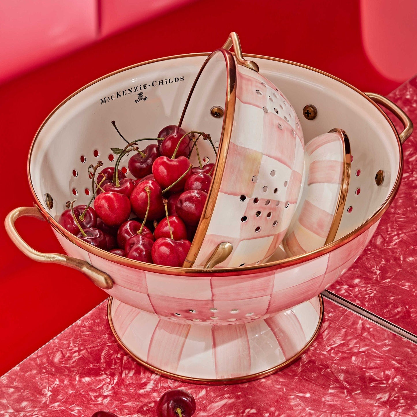 Velký smaltovaný cedník Rosy Check od MacKenzie-Childs, v růžovém kostkovaném designu s mosaznými rukojeťmi, Waterfall Bathrooms.