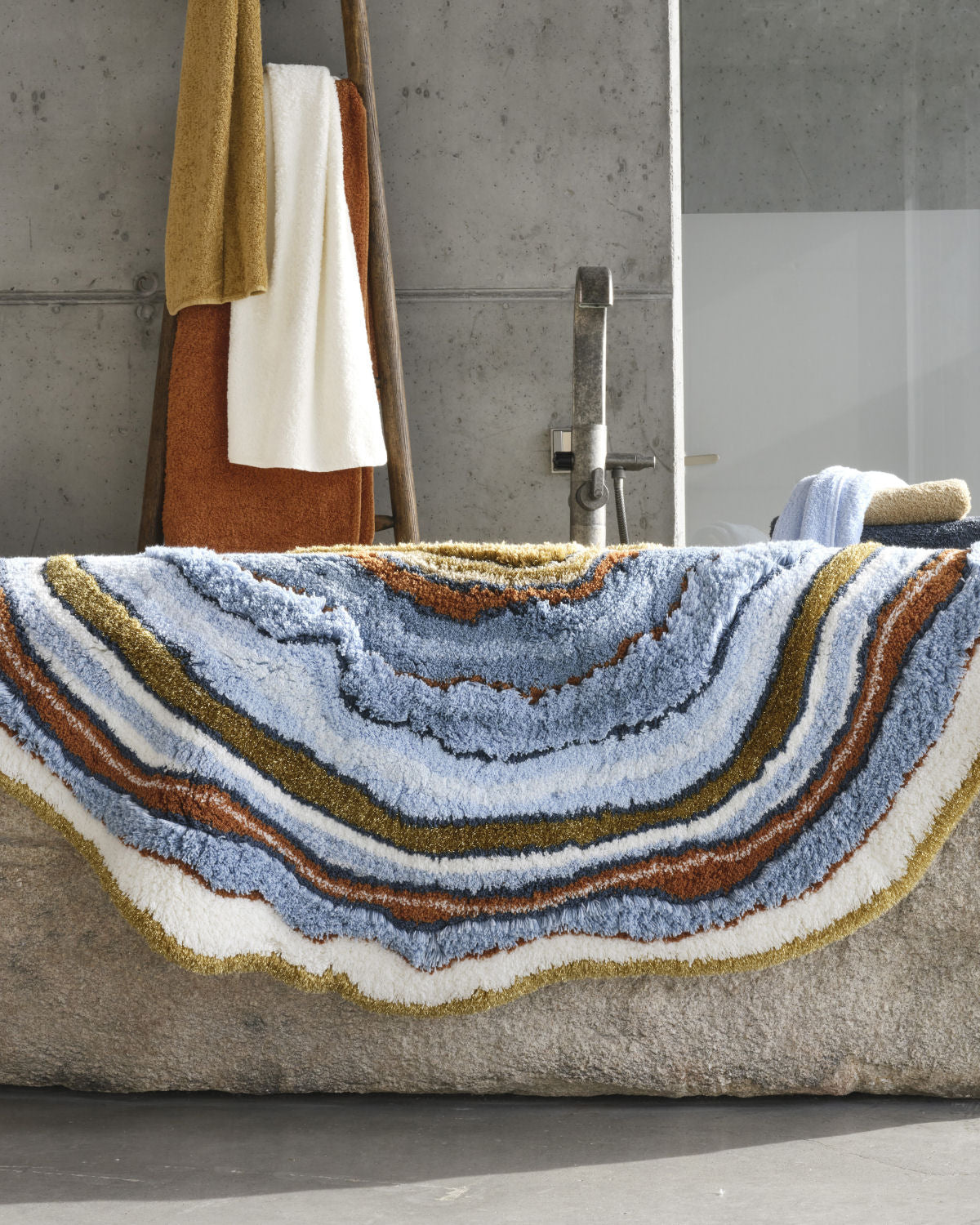 Luxusní designová koupelnová předložka Celora od Abyss & Habidecor v asymetrickém tvaru s modrými, béžovými a zlatými tóny Waterfall Bathrooms