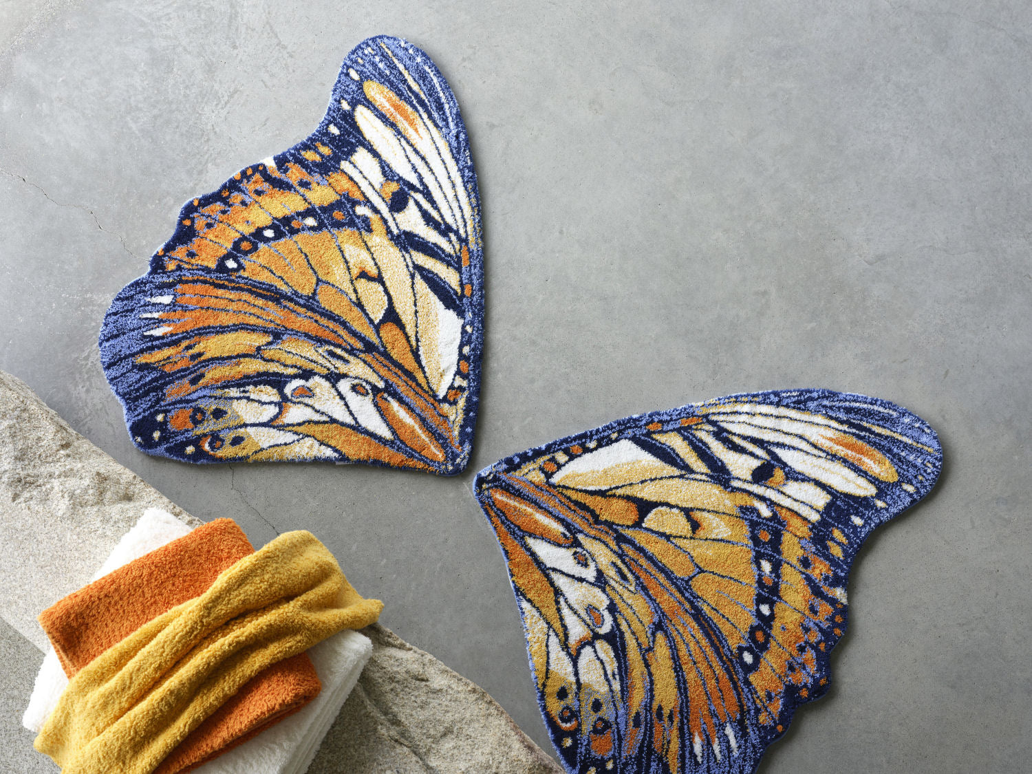 Luxusní koupelnová předložka Mariposa od Abyss & Habidecor ve tvaru detailně vykresleného oranžového a tmavě modrého motýlího křídla Waterfall Bathrooms