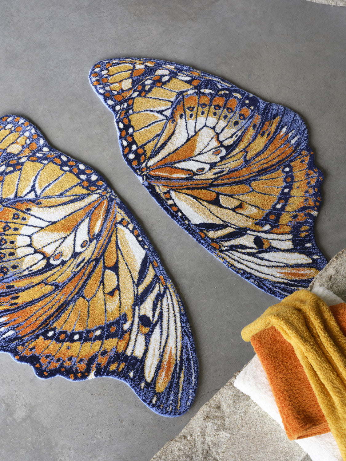 Luxusní koupelnová předložka Mariposa od Abyss & Habidecor ve tvaru detailně vykresleného oranžového a tmavě modrého motýlího křídla Waterfall Bathrooms