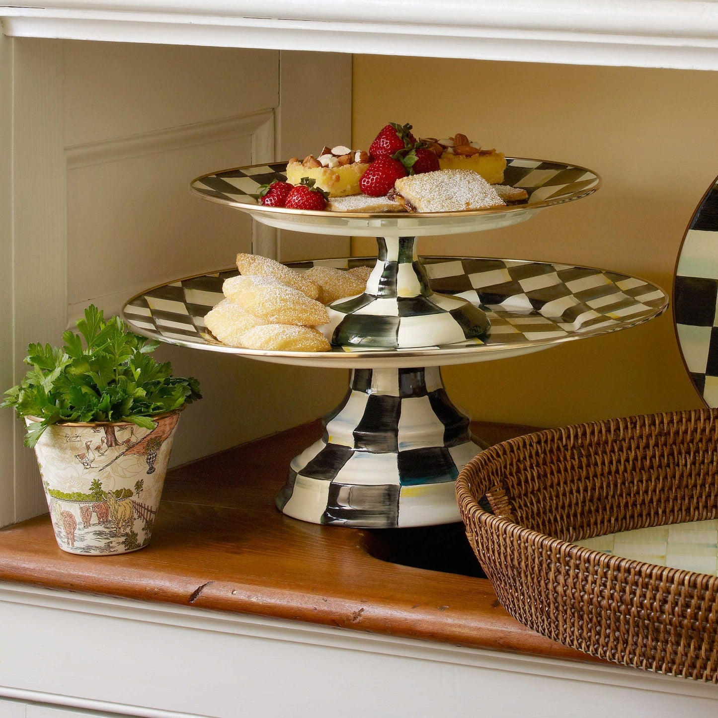 Velký servírovací tác na podstavci Courtly Check od MacKenzie-Childs s černobílým kostkovaným vzorem a bronzovým lemováním, Waterfall Bathrooms.
